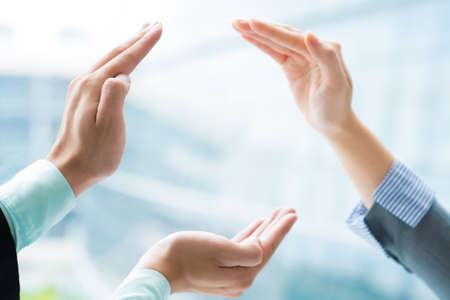 Image of human hands making a circle taking care from something on the foregroundの写真素材