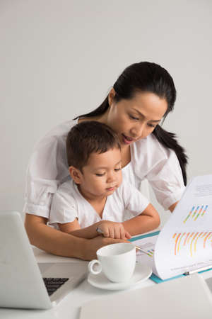 Vertical image of a mom and her little son working together at homeの写真素材