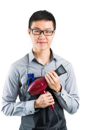 Vertical portrait of a young professional stylist with a hairdryer in hands over a white backgroundの写真素材