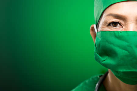 Copy-spaced portrait of a female doctor in mask isolated on greenの写真素材
