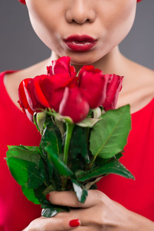 Vertical image of a lady holding red roses on the foregroundの写真素材