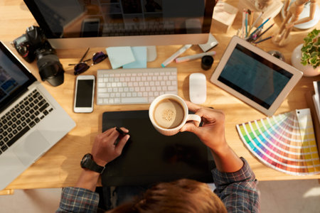 Web designer drinking coffee at workplace, view from aboveの写真素材