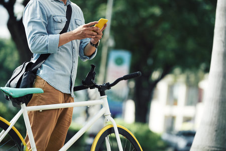 Man with bicycle standing in the street and checking smartphone