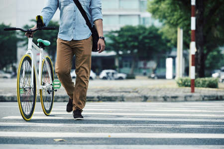 Man walking next to his bike when crossing the roadの写真素材