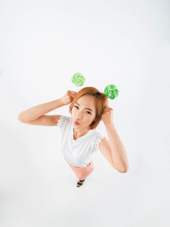 Funny Korean girl making ears with green lollipops, view from aboveの写真素材