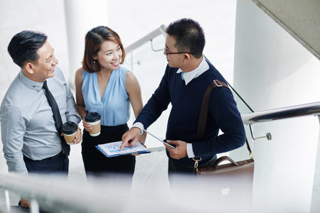 Vietnamese business people discussing financial report during the break