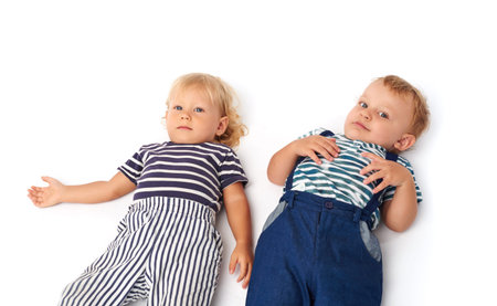 Two little boys lying on white floorの写真素材