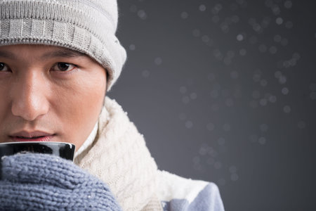 Close-up of a man in warm hat drinking hot beverageの写真素材