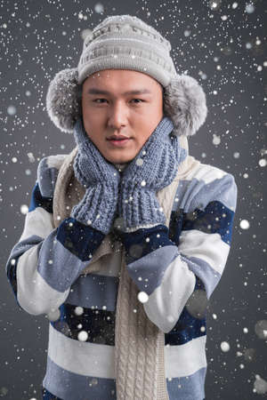 Vertical portrait of a young man wearing in warm clothes because of the nippy snowy weatherの写真素材