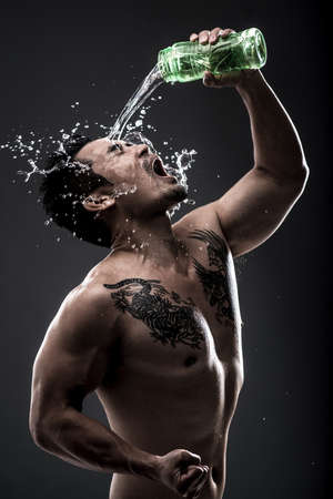 Vertical image of a masculine man pouring water over himselfの写真素材