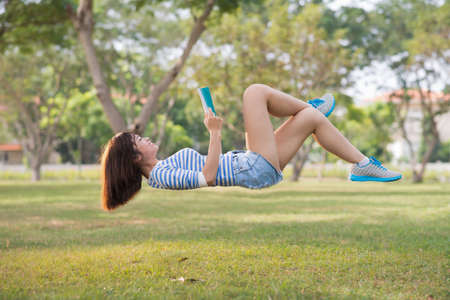 Girl lying in the air with a bookの写真素材