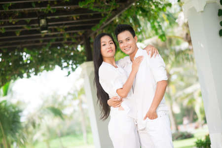 Copy-spaced portrait of a young romantic couple cuddling and looking at cameraの写真素材