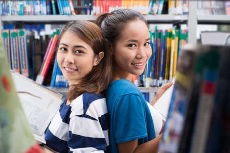 Portrait of two cheerful girls in libraryの写真素材