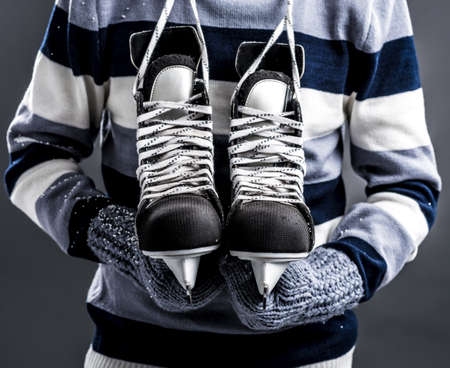Close-up image of a man holding hockey skates over a grey backgroundの写真素材