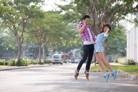 Two teenage friends jumping with phonesの写真素材