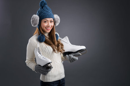 Isolated portrait of a young woman standing with figure skates and posing at cameraの写真素材