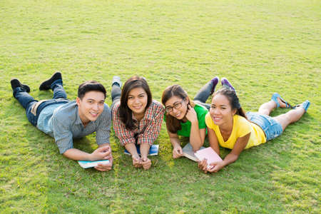 Portrait of four students posing on lawnの写真素材