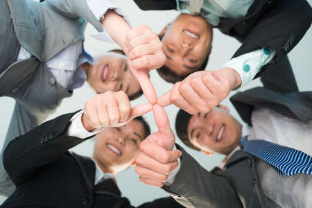 Angle view of a business team joining their fingers together in the sign of unity on the foregroundの写真素材