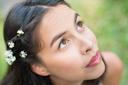 Close-up of a young attractive woman with daisy flowers in hairの写真素材