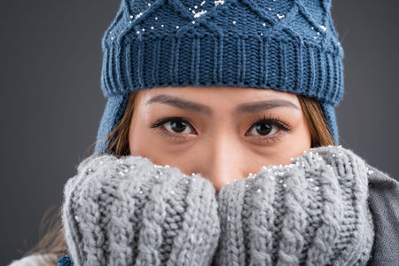 Close-up portrait of a young woman in winter clothes looking at cameraの写真素材