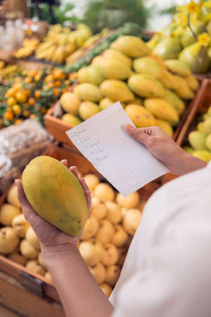 Cropped image of a woman shopping in the market according the shopping listの写真素材