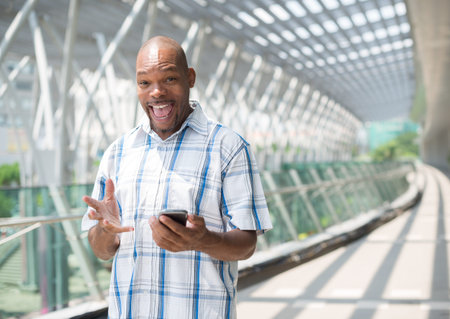 Copy-spaced portrait of a cheerful black businessman with a gadget in handsの写真素材