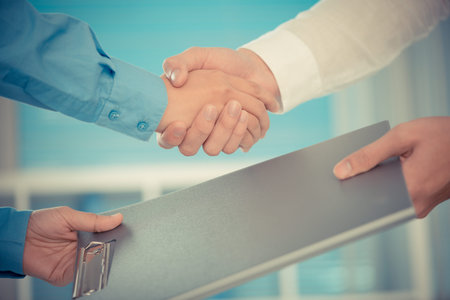 Cropped image of human handshaking after signing a contract on the foregroundの写真素材