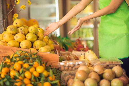 Cropped image of a saleswoman suggesting to buy a great variety of fresh fruitの写真素材