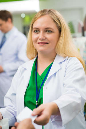 Vertical image of a saleswoman giving credit card to the client after payment on the foregroundの写真素材