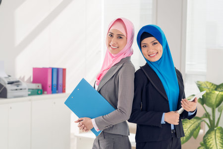 Two Vietnamese business ladies standing with documents in the officeの写真素材