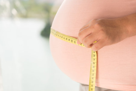 Close-up of female pregnant belly with tape measure