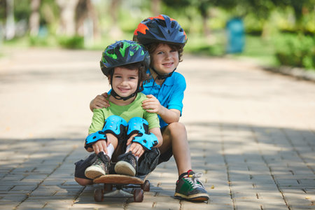 Little boys sitting on skateboard in park