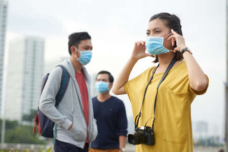 Asian woman putting on protective maskの写真素材