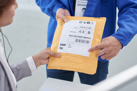 Delivery man showing business woman where she should write shipping addressの写真素材