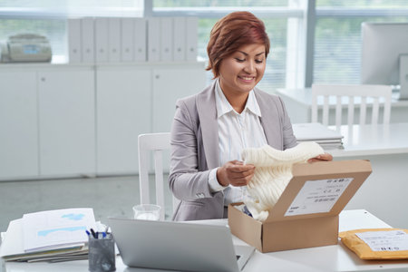 Business lady receiving parcel with sweater at workの写真素材