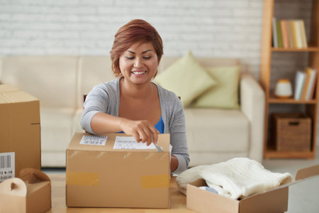 Happy Vietnamese woman opening many parcels at home
