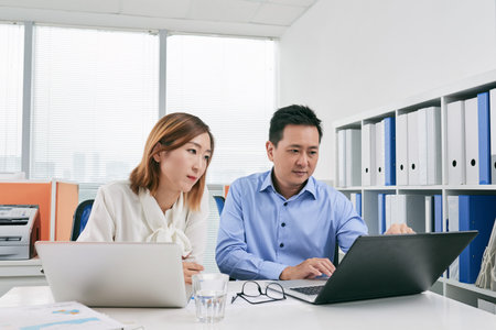 Asian business people using laptops at meeting in office