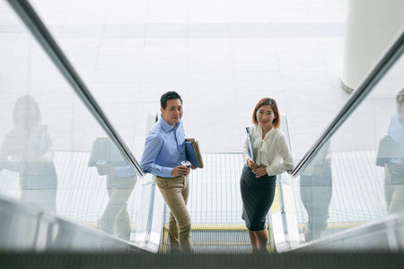 Cheerful business people standing on escalator, view from aboveの写真素材