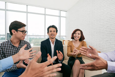 Happy Asian business people clapping at meeting