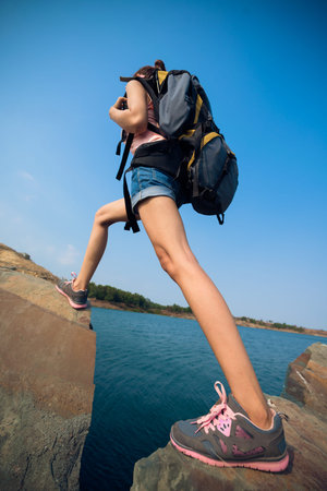 Hiker with backpack climbing rocky terrain, focus on legs