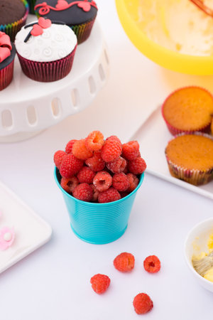 Close-up image of a glass with fresh raspberries for cake preparation on the foreground