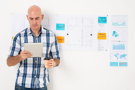 Image of a businessman in casual with tablet and coffecup with detailed business plan of company
