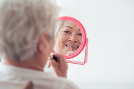 Pretty aged woman putting on lipstick, rear view