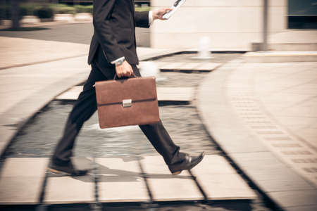 Man reading newspaper while hurrying to workの写真素材