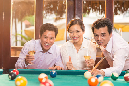 Friends cheering a man while he is hitting the billiard ball
