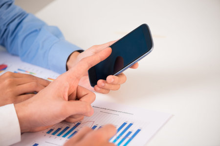 Close-up of colleagues using smartphone