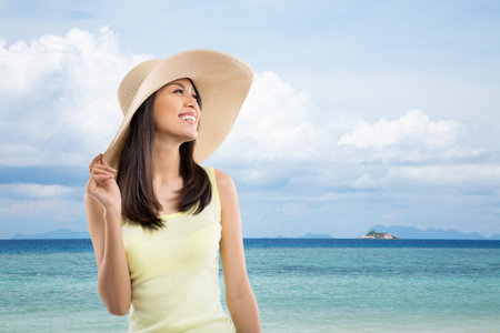 Portrait of Asian lady in a straw hat enjoying her time on the beachの写真素材