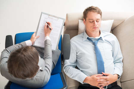 Young businessman having consultation with the psychologist, view from the topの写真素材