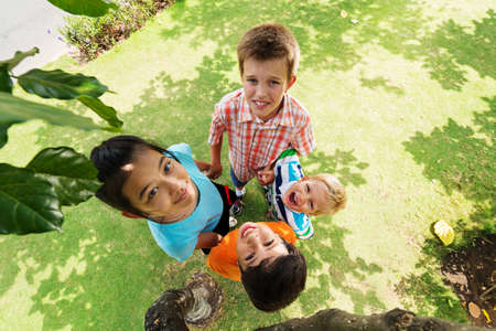Four kids holding their hands and looking at the camera, view from the topの写真素材