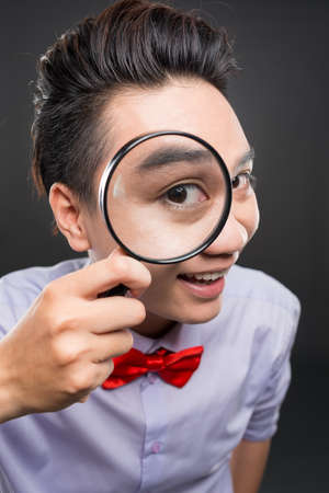 Close-up of young Vietnamese man looking through magnifierの写真素材